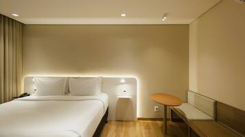 Una habitación de hotel con cama, mesita de noche y un banco.