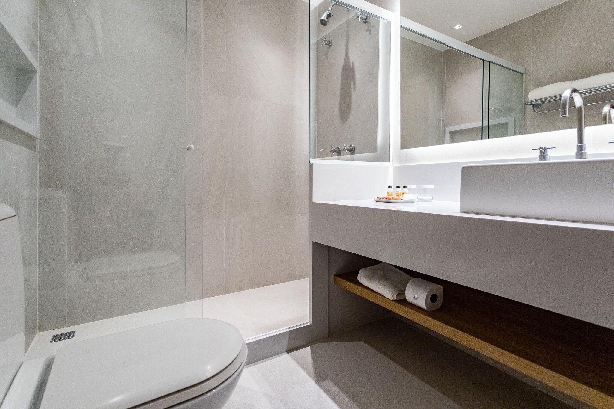 Une salle de bain moderne avec une douche à parois de verre, un lavabo blanc et des toilettes.