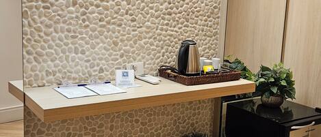 A reception desk with a stone wall backdrop, a coffee machine, and potted plants.