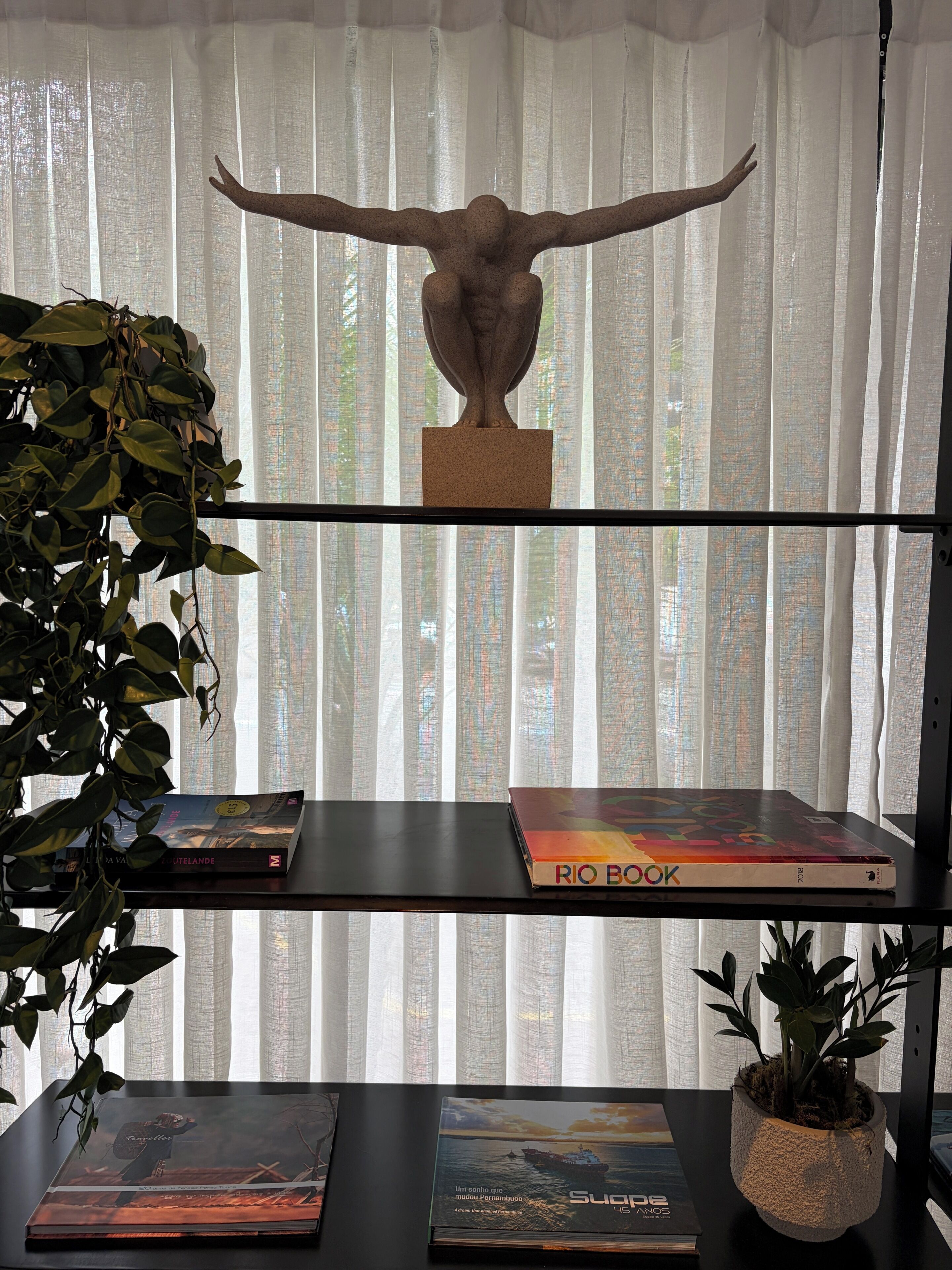 A bookshelf with books and a sculpture.