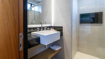 A modern bathroom with a white sink, black countertop, and a glass shower enclosure.