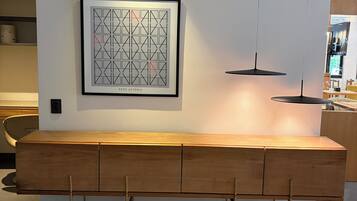 Uma cozinha moderna com um banco de madeira, luminárias pendentes e uma obra de arte emoldurada na parede.