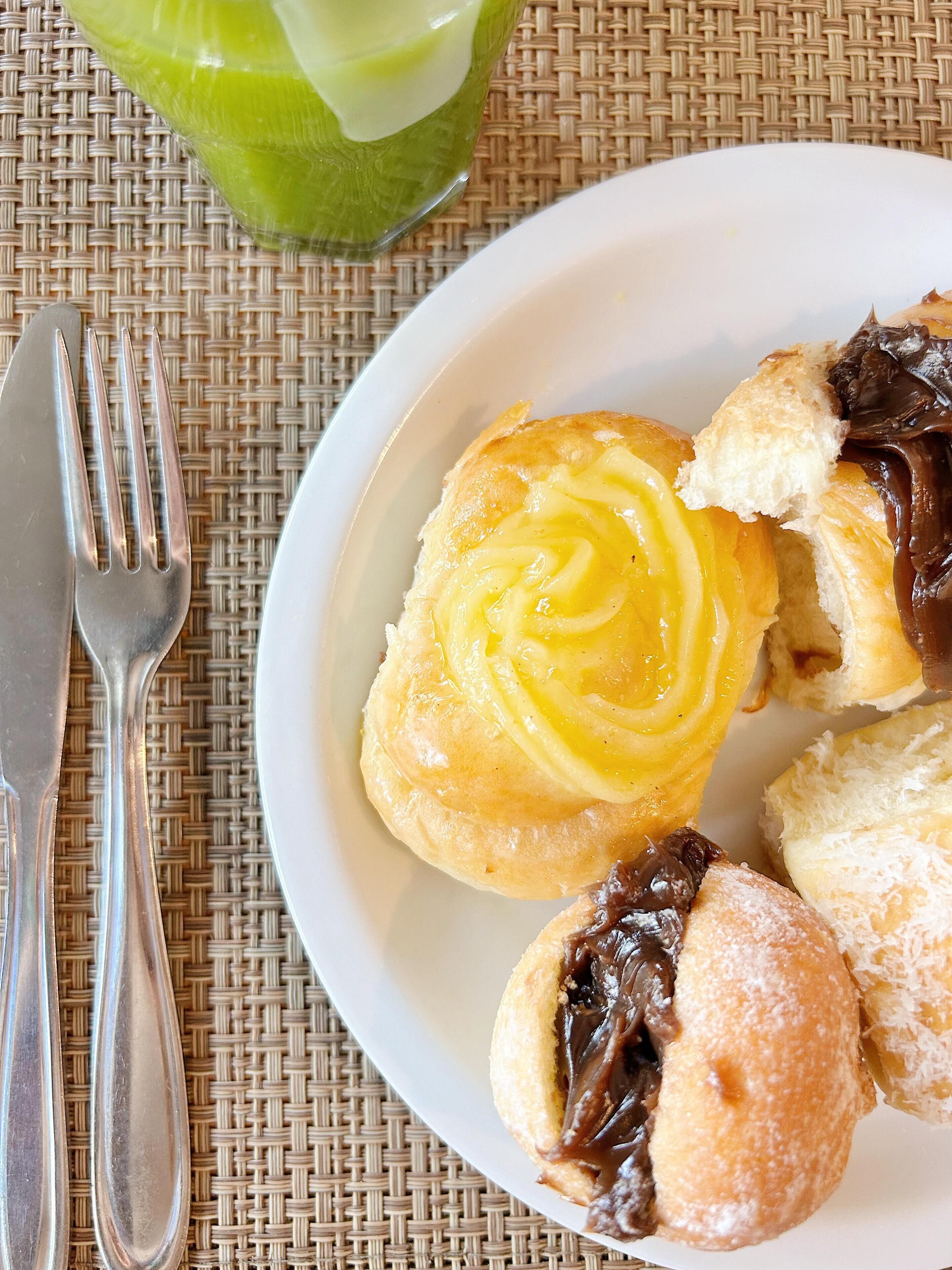 A plate with pastries and a fork on a woven mat.