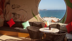 Un rincón acogedor con vistas al mar a través de un amplio ventanal circular.