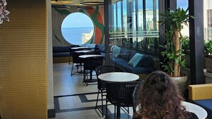 Un espacio al aire libre con vistas al mar, con mobiliario de mimbre y plantas en macetas.