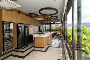 Eine moderne Küche mit integrierten Geräten, einer Holzausziehtheke und Blick auf Grünpflanzen durch große Fenster.