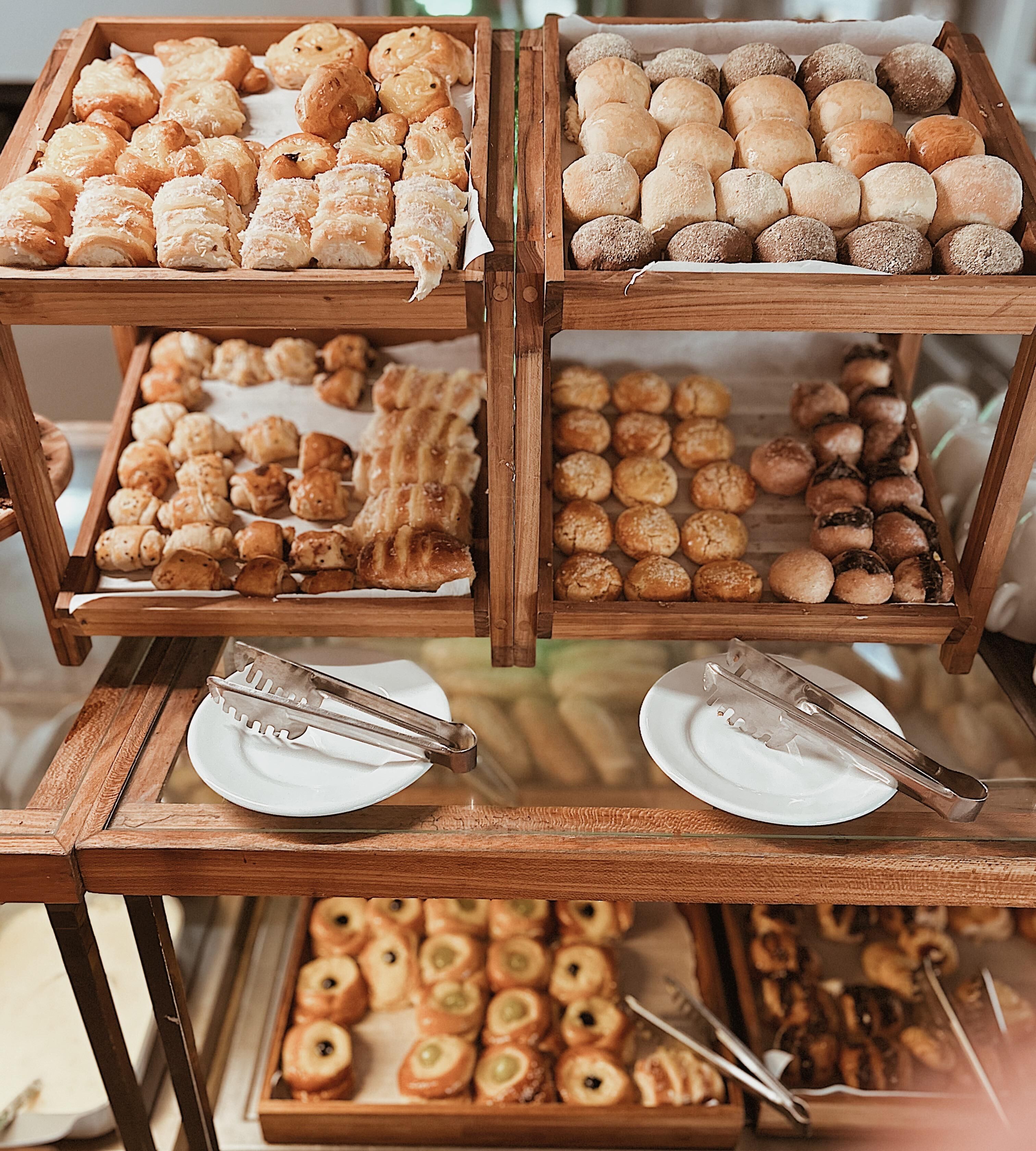 Une vitrine en bois contenant divers produits de boulangerie, notamment des pâtisseries et du pain, disposés en plusieurs sections.