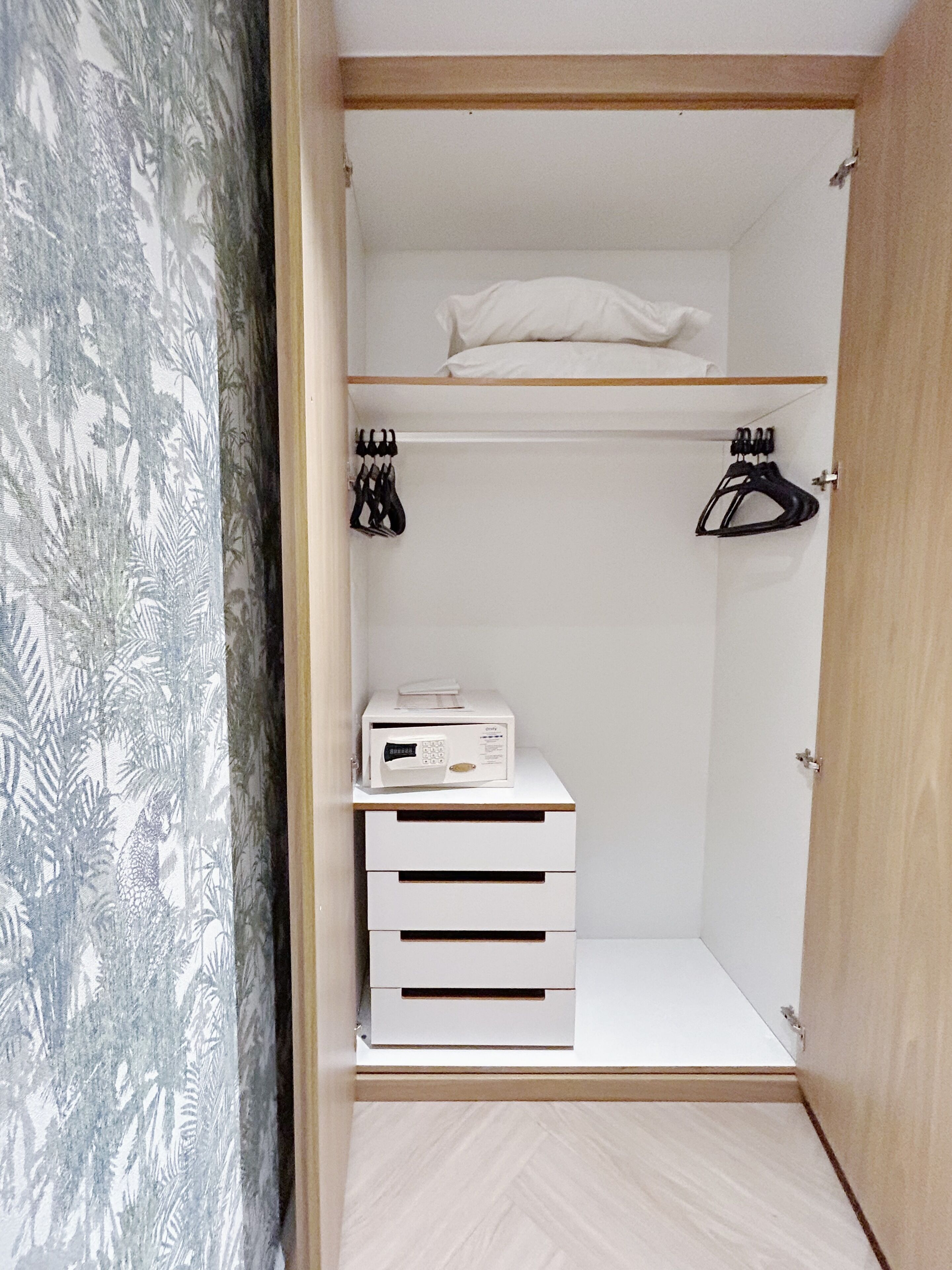 A walk-in closet with a wooden floor, a white storage unit, and a white appliance on top.