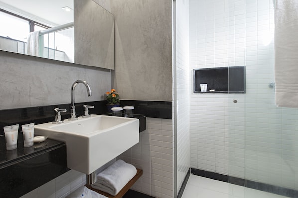 Un baño moderno con un lavamanos grande, espejo y zona de ducha.