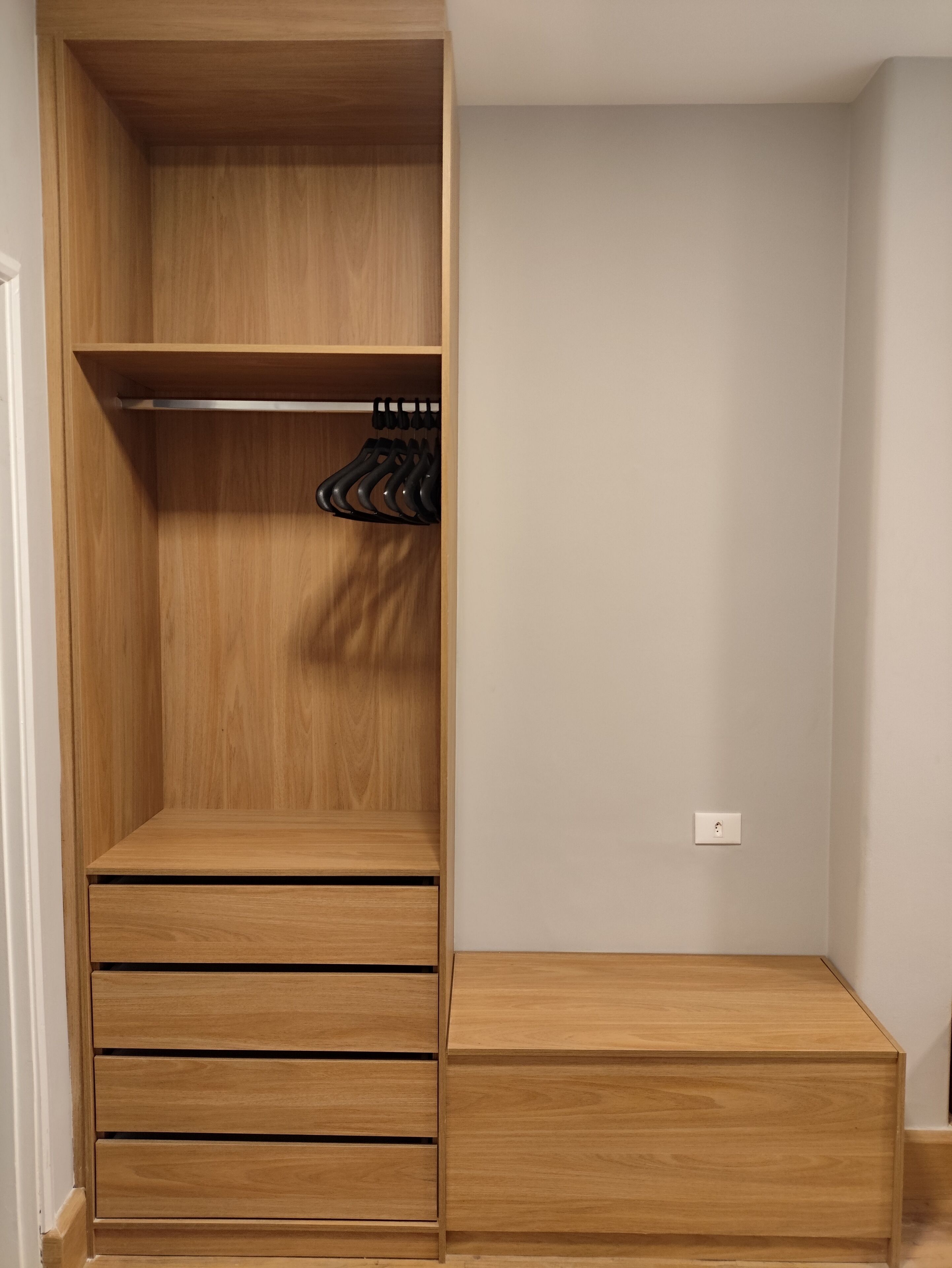 A wooden closet with open shelves, a hanging rack, and a bench.