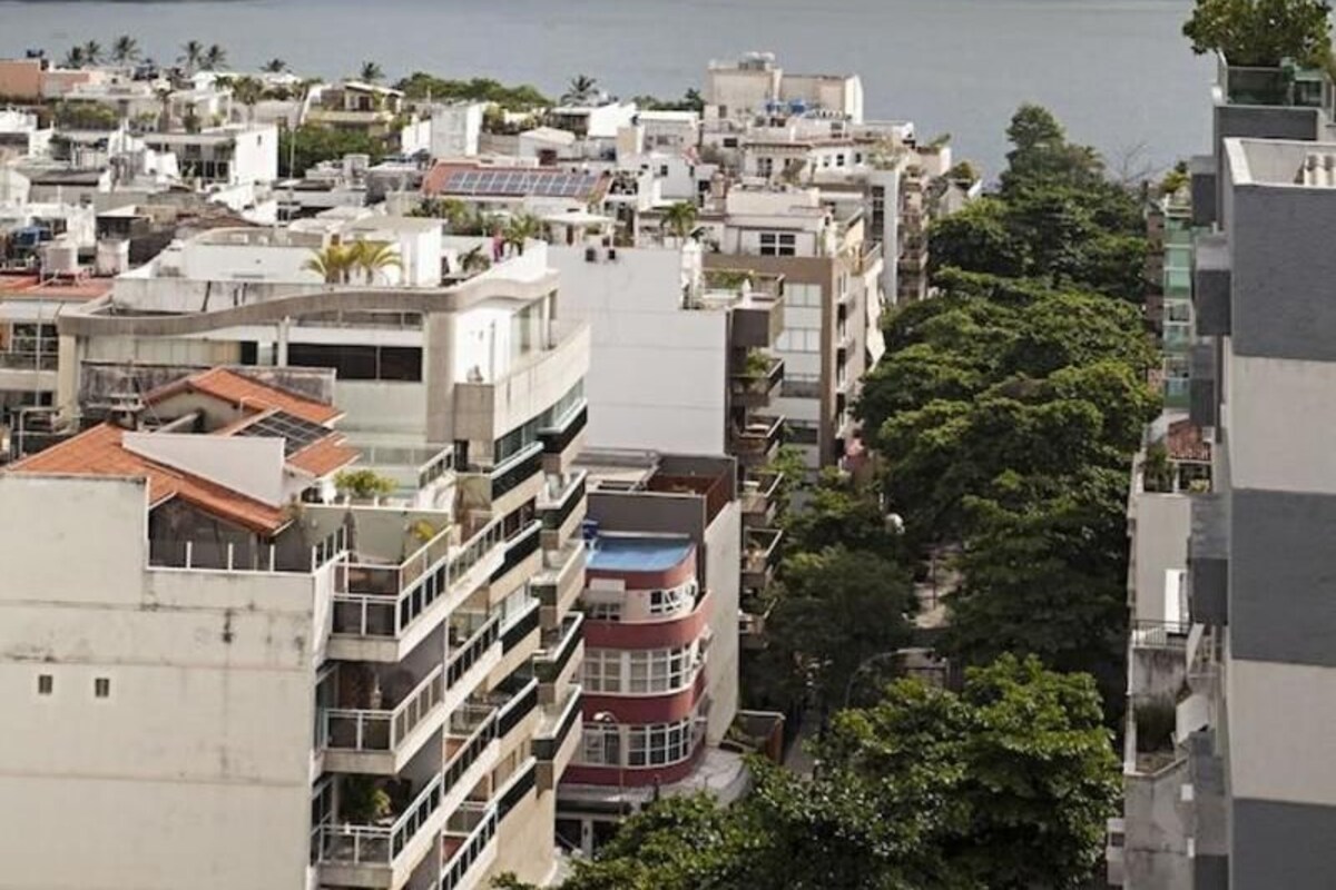 A coastal cityscape with a prominent mountain in the background, residential buildings, and a body of water.