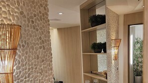 Un interior moderno con una pared texturizada, piso de madera, un armario espejado y una planta en maceta.