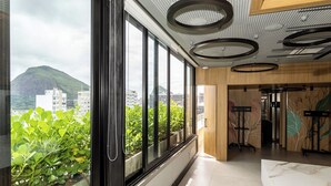 Habitación de hotel moderna con ventanas amplias, vistas a la montaña e iluminación circular en el techo.