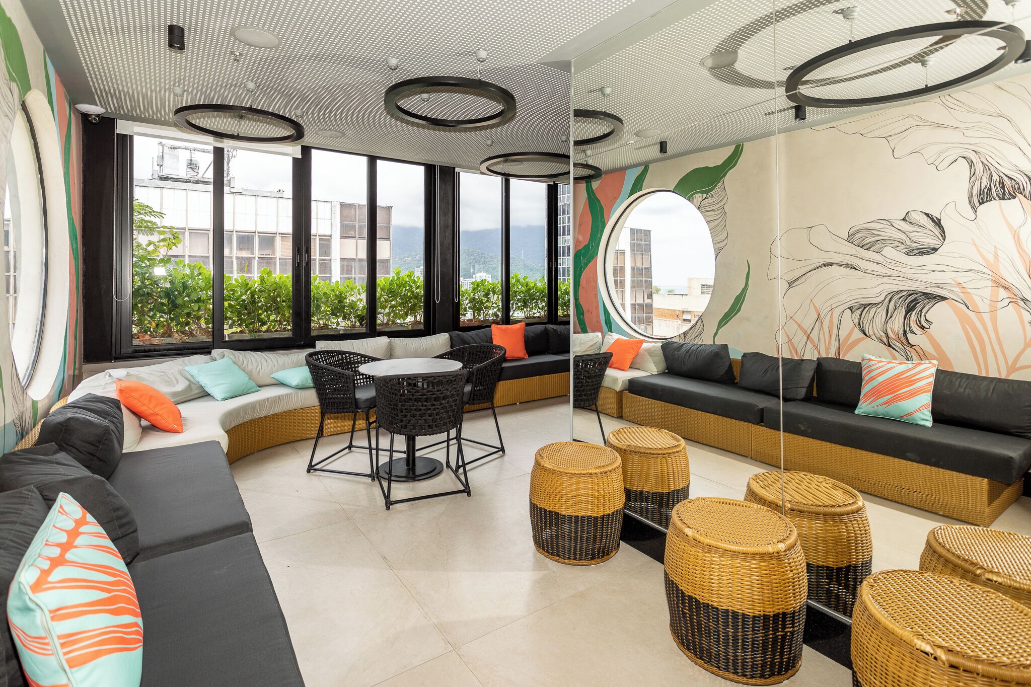 Een moderne zithoek met een bank, stoelen, rieten krukjes en een ronde tafel.