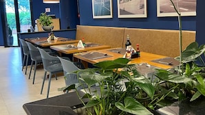 A modern dining area with a long table, blue walls, and framed cityscape pictures.