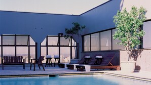 A modern pool area with lounge chairs and a view of the cityscape. - L'Hirondelle Flat Service (Campinas)