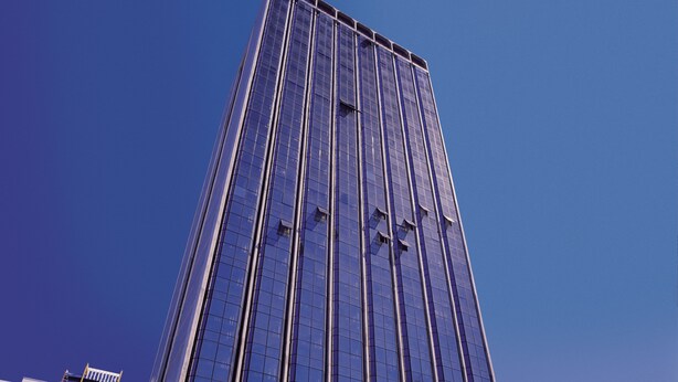 A tall, modern skyscraper with a glass facade, surrounded by palm trees and other buildings. - L'Hirondelle Flat Service (Campinas)