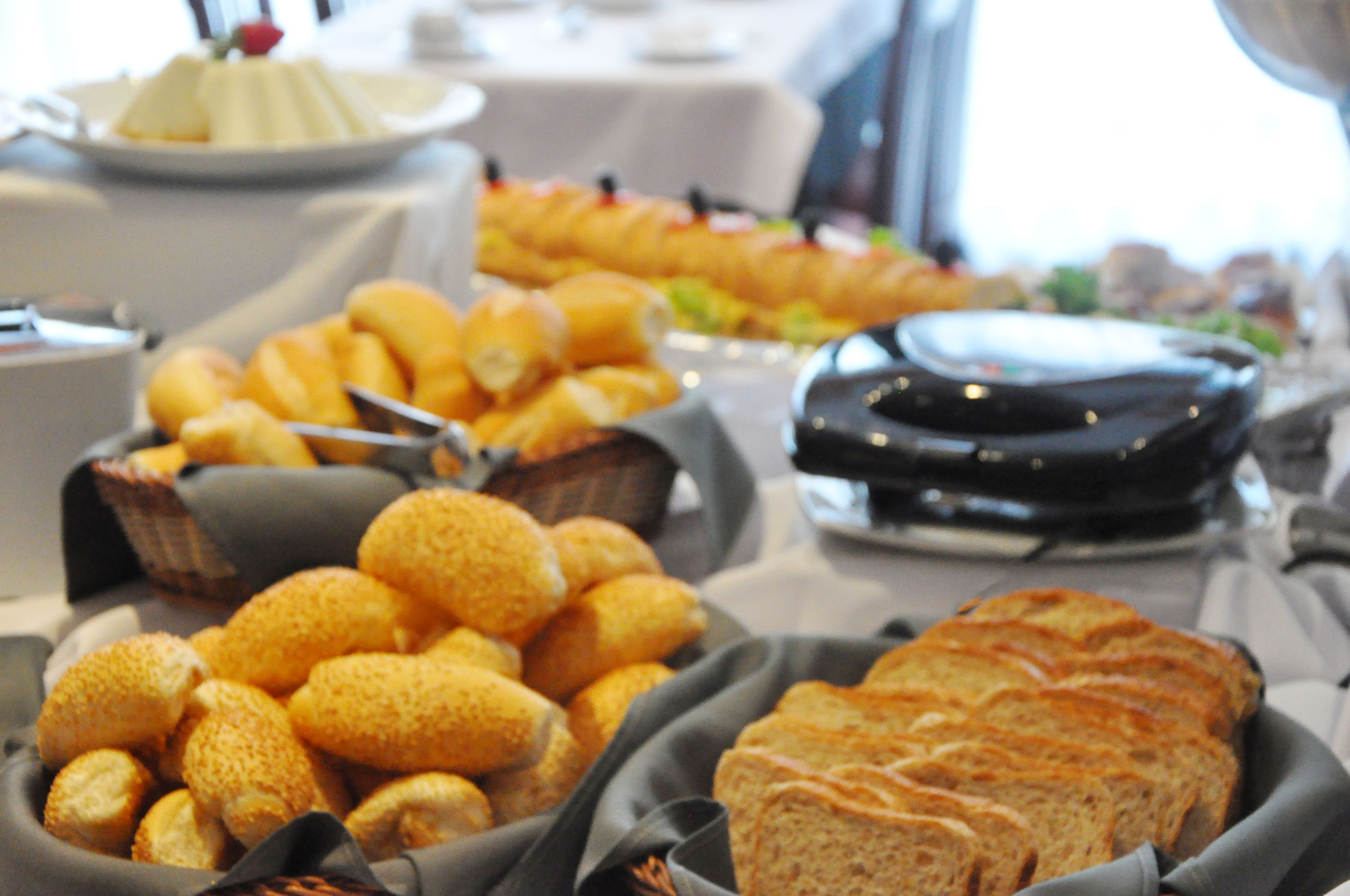 Une table de buffet proposant divers aliments, notamment des petits pains, des pâtisseries et un gâteau.