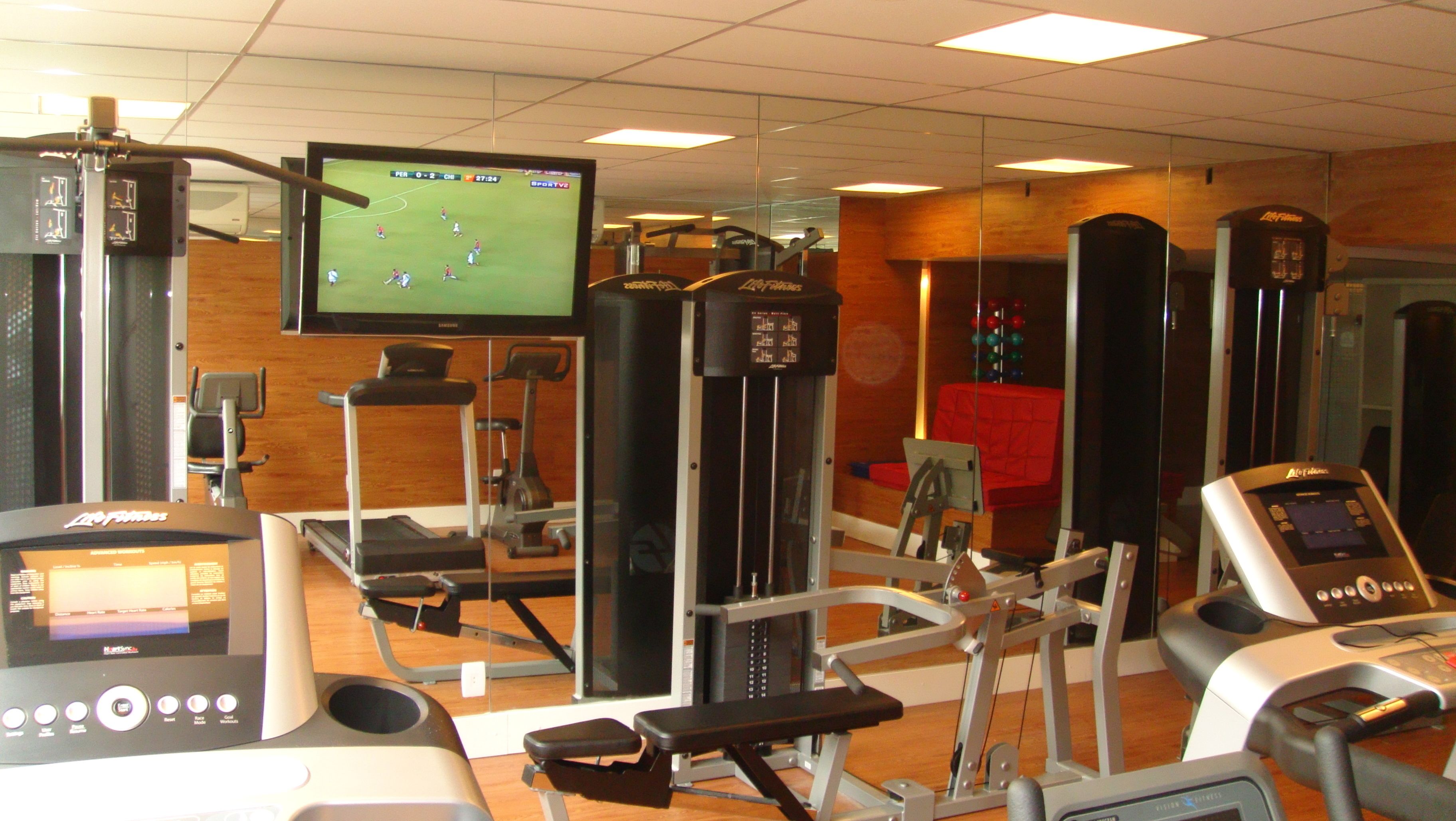 A gym with various exercise equipment, including treadmills, a stationary bike, and a weight machine.