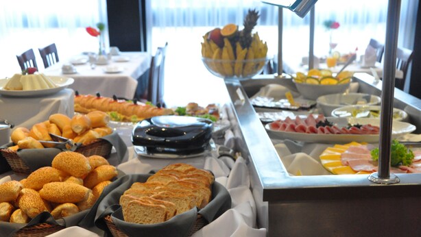 Un bufé con diferentes opciones de comida, incluyendo pan, frutas y carnes.