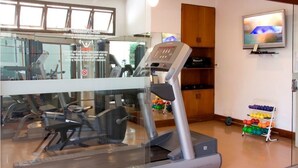 Een sportschool met een hometrainer, loopband en krachtapparaten.
