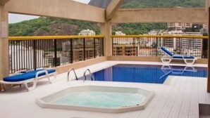 Een zwembadterras met twee whirlpools en ligbedden.