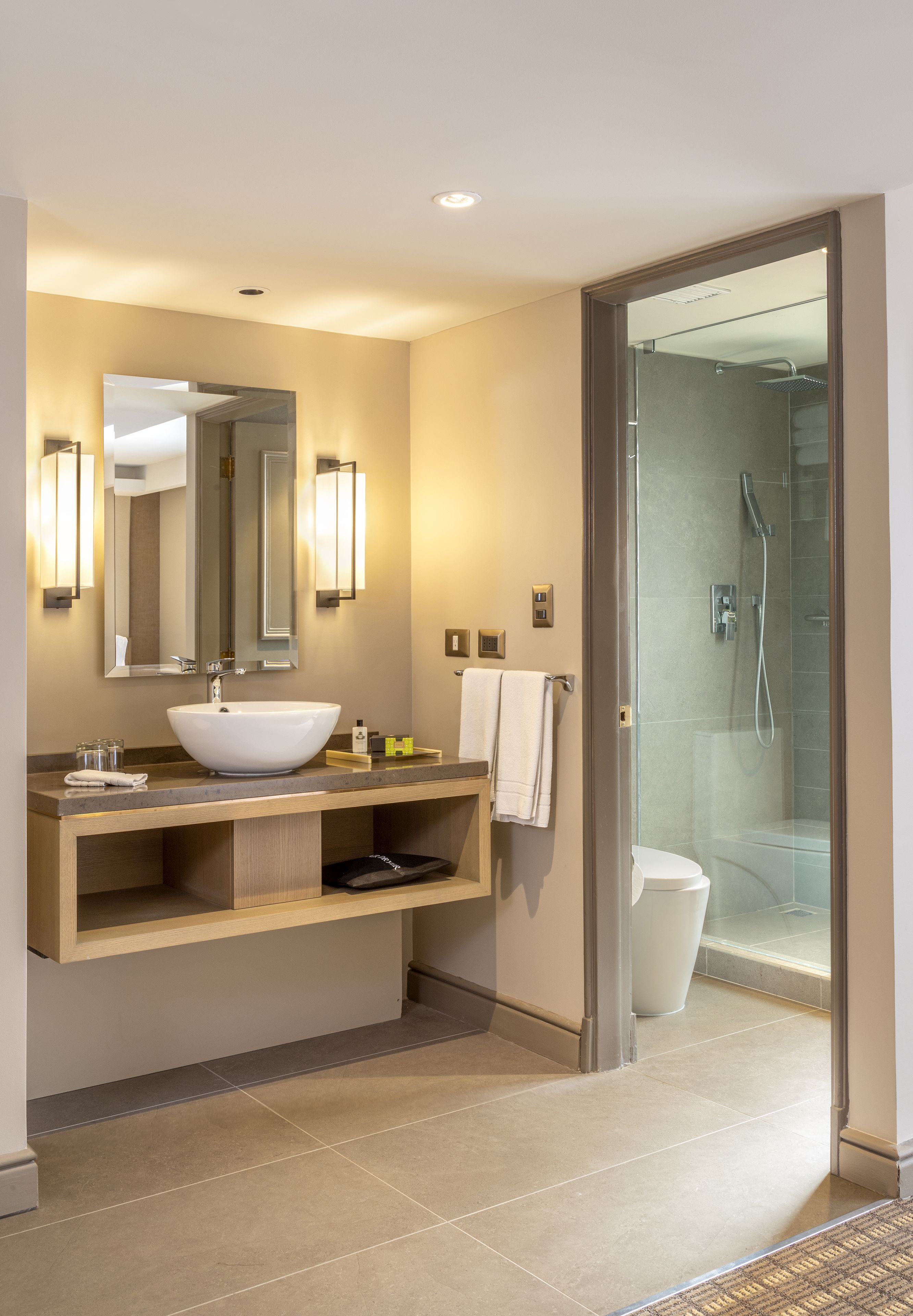 Un baño moderno con un lavamanos grande, espejo y ducha.