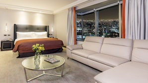 A hotel room with a bed, a sofa, a glass coffee table, and a view of a cityscape at night. - InterContinental Santiago by IHG (Santiago)
