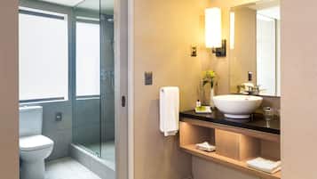 A modern bathroom with a glass-enclosed shower, a white toilet, a sink with a mirror, and a towel rack.