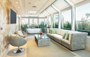 A modern living room with a sofa, armchair, and coffee table, large windows with city views, and a patterned wall. - InterContinental Santiago by IHG (Santiago)