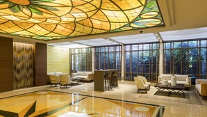 A spacious lobby with a large, polished floor, a central seating area with sofas and chairs, and large windows offering views of greenery. - InterContinental Santiago by IHG (Santiago)