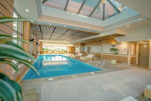 An indoor swimming pool with lounge chairs and a glass ceiling. - InterContinental Santiago by IHG (Santiago)