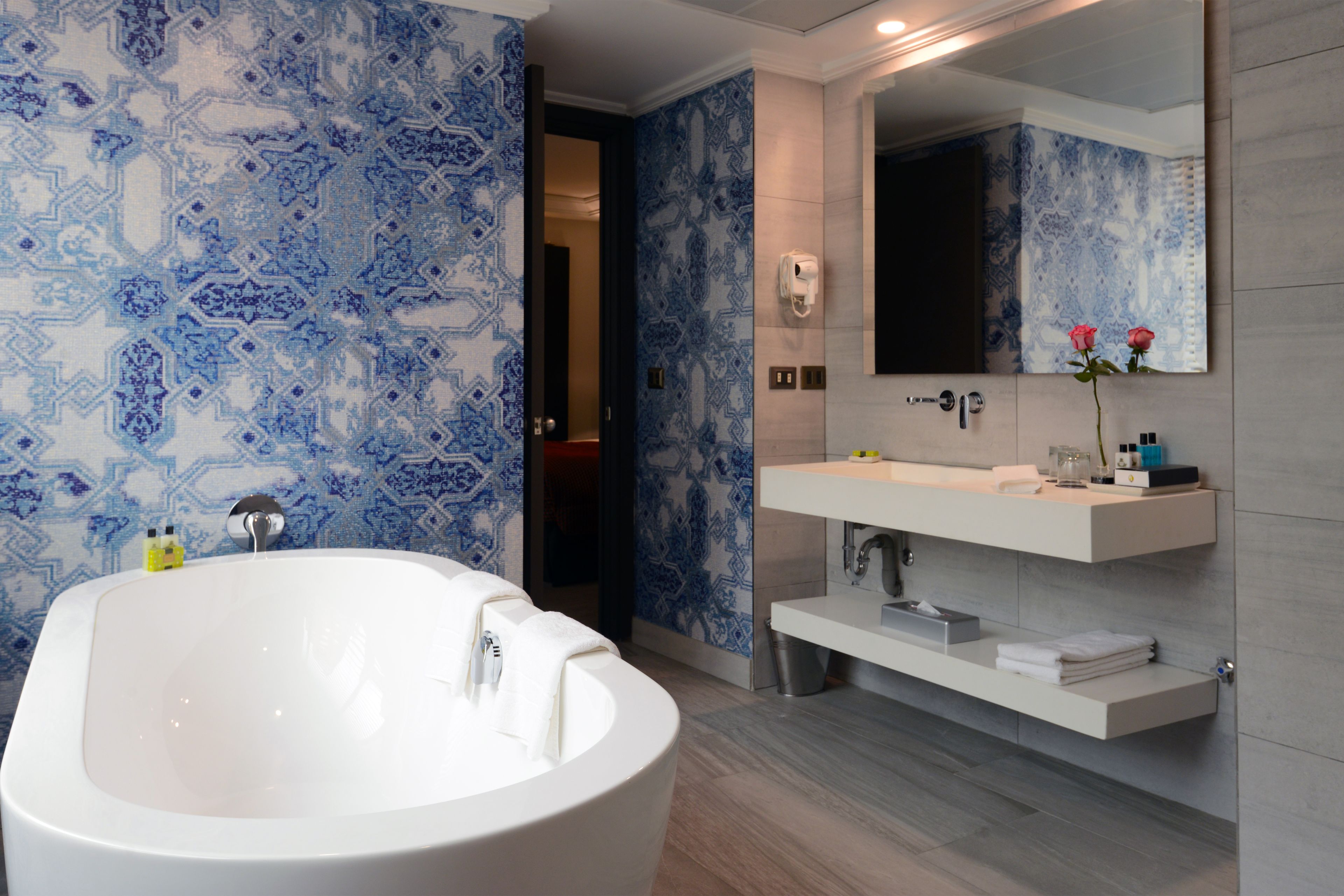 A modern bathroom with a freestanding bathtub, a large mirror, and a vanity with a sink and towel rack.