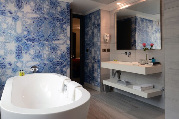 Une salle de bain moderne avec une baignoire sur pieds, un grand miroir et un meuble-lavabo doté d’un évier et d’un porte-serviettes.