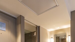 Ein modernes Badezimmer mit großem Spiegel, Waschbecken und Duschbereich.