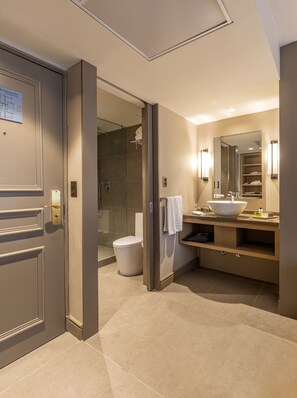 A modern bathroom with a large mirror, a sink, and a shower area.