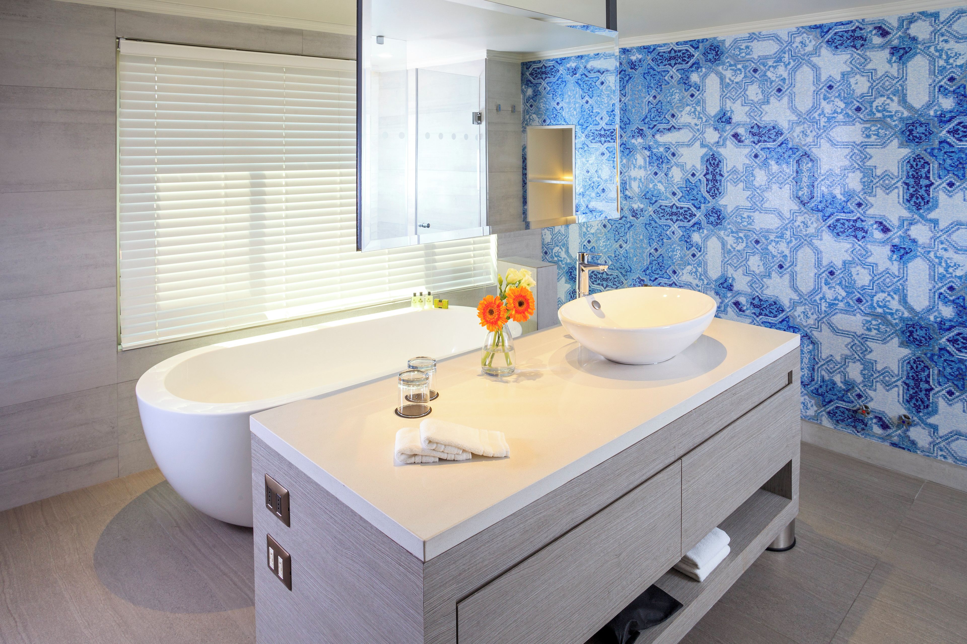 A modern bathroom with a freestanding bathtub, a large sink with a bowl, and a vanity with drawers.