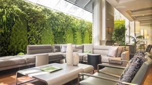 Ein modernes Wohnzimmer mit grüner Wand, einem Ecksofa, einem Couchtisch und einem Sessel.
