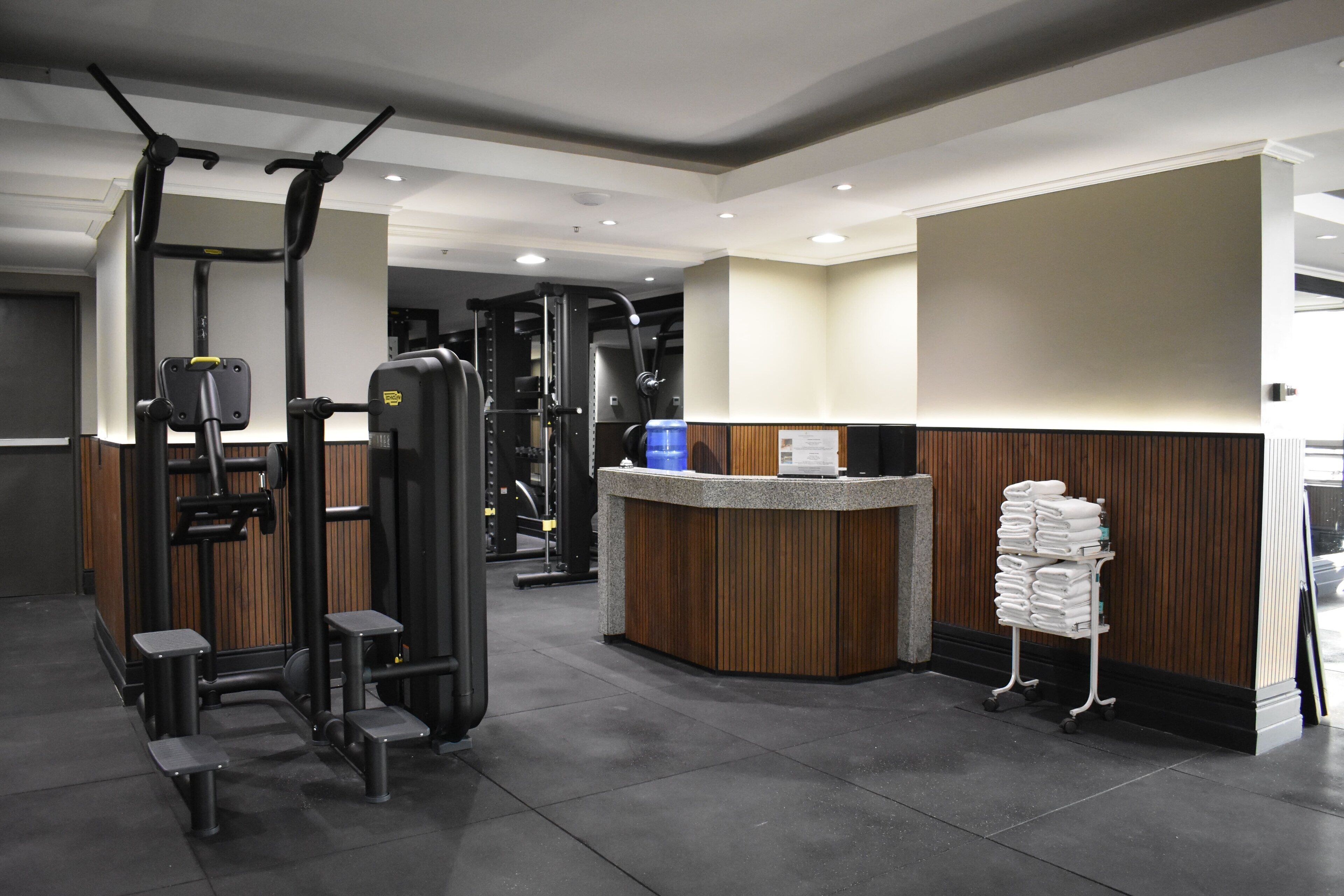 A gym with various exercise machines, a reception desk, and a towel rack.