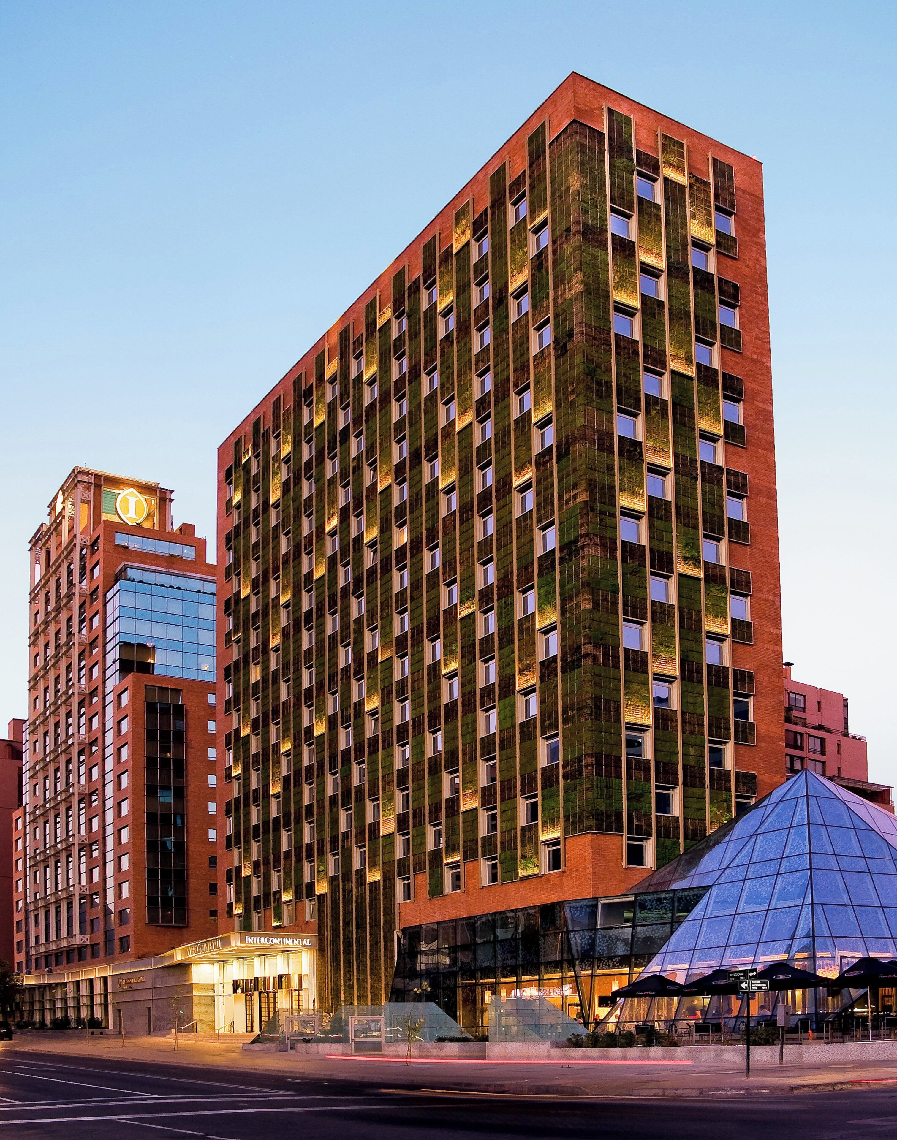 A high-rise building with a distinctive facade featuring vertical green panels and a prominent corner entrance.