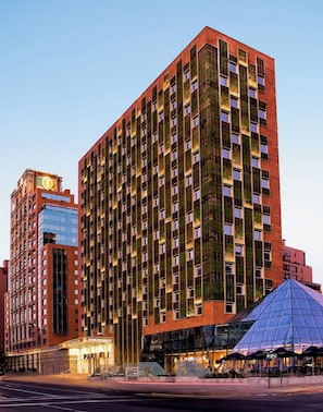 A high-rise building with a distinctive facade featuring vertical green panels and a prominent corner entrance. - InterContinental Santiago by IHG (Santiago)