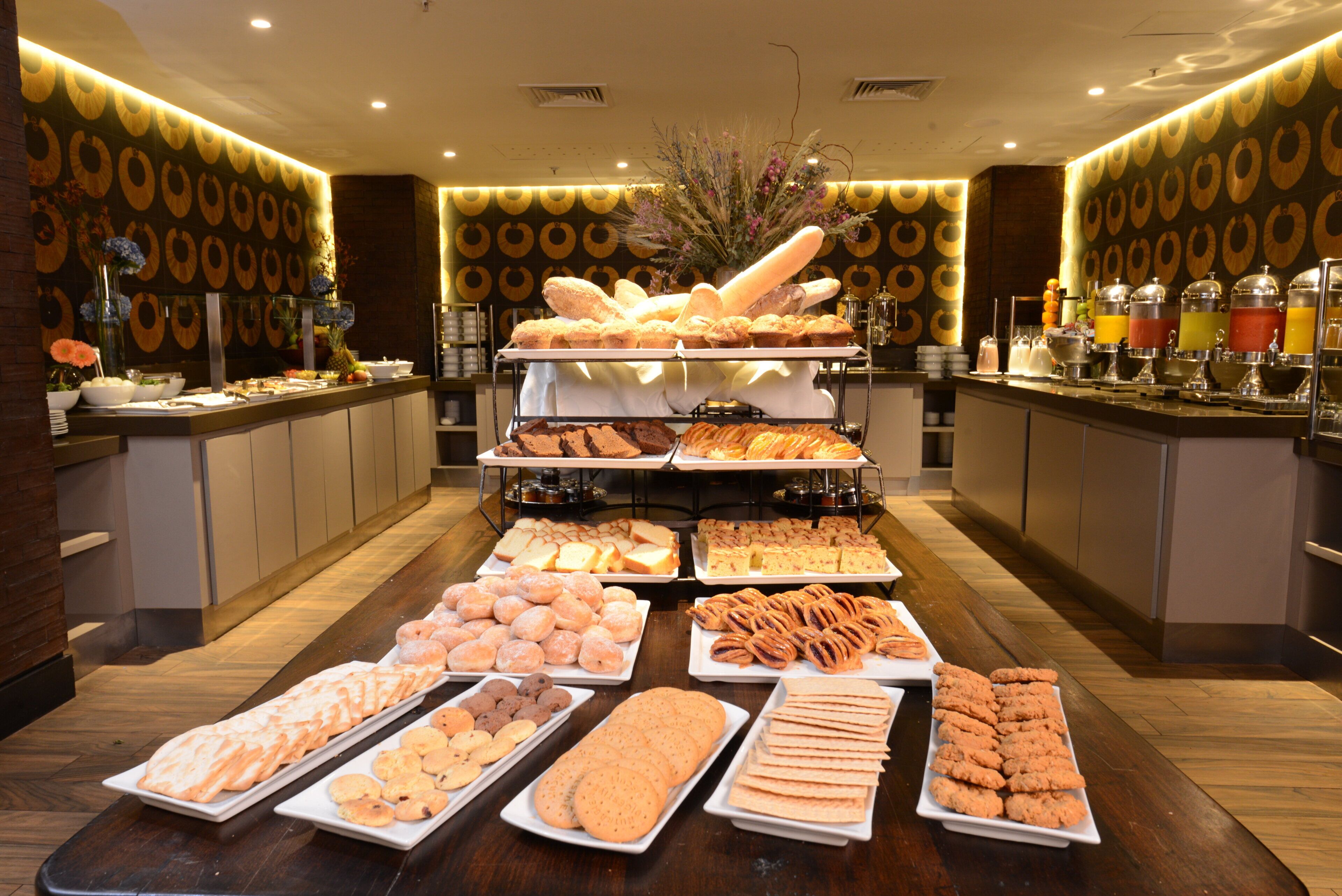 A buffet with various food items and a decorative wall with circular patterns.