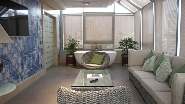 A modern bathroom with a freestanding bathtub, a wicker chair, and a sofa with patterned cushions. - InterContinental Santiago by IHG (Santiago)