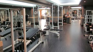 Ein Fitnessstudio mit verschiedenen Trainingsgeräten, Spiegelwänden und einem Oberlicht.