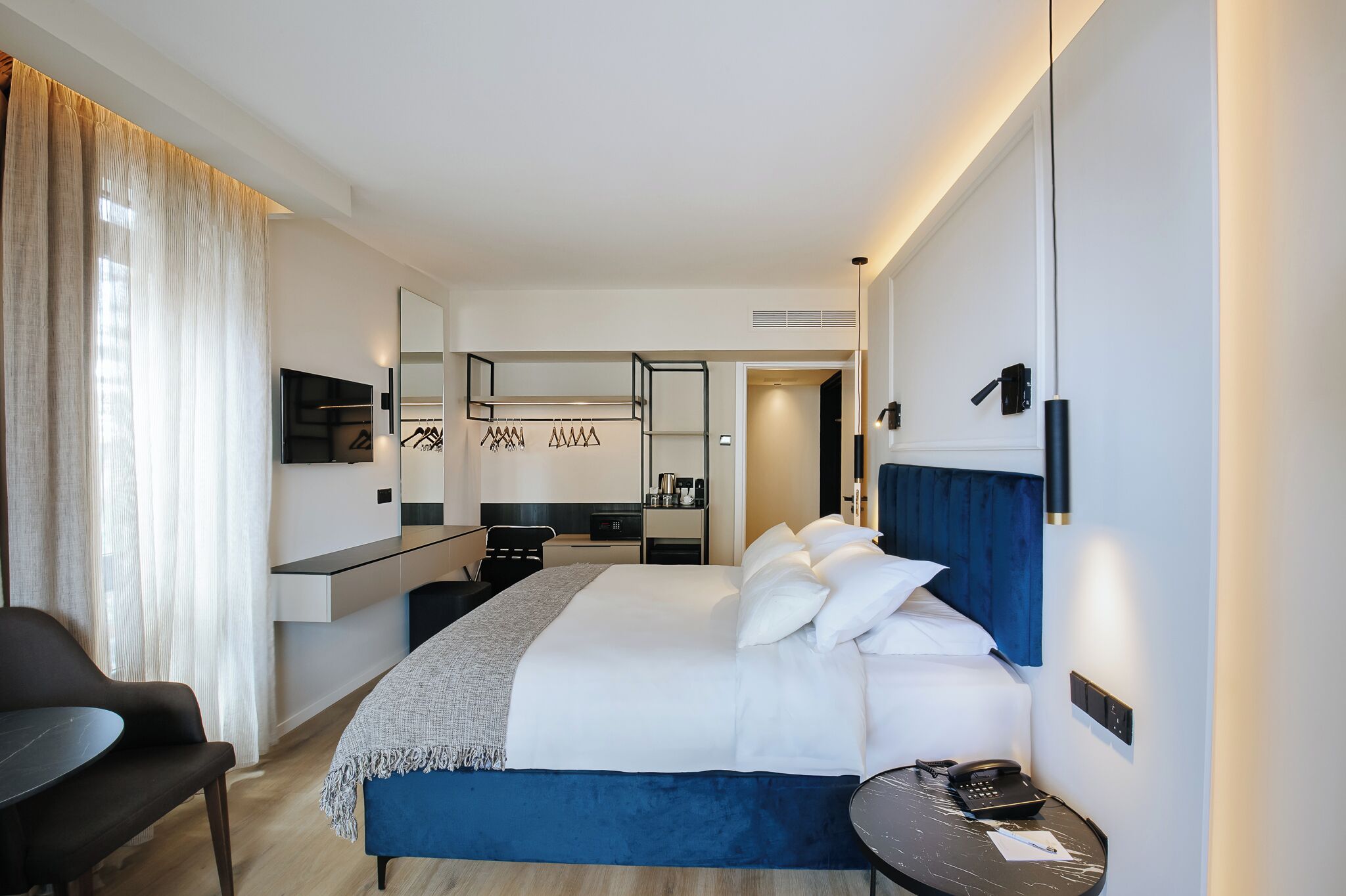 Une chambre d’hôtel comprenant un lit, une table de chevet, une chaise, un bureau et un miroir.
