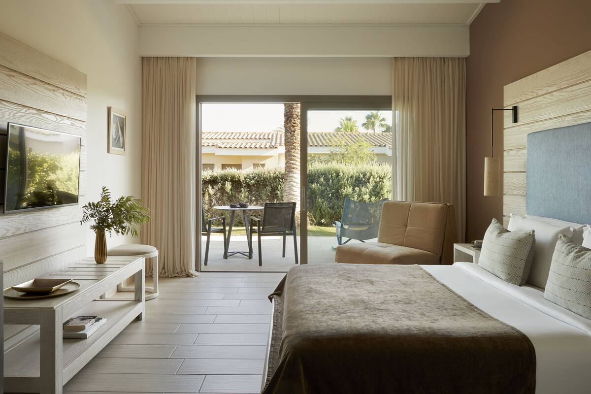 Een hotelkamer met een groot bed, een televisie, een bureau en een balkon met uitzicht.