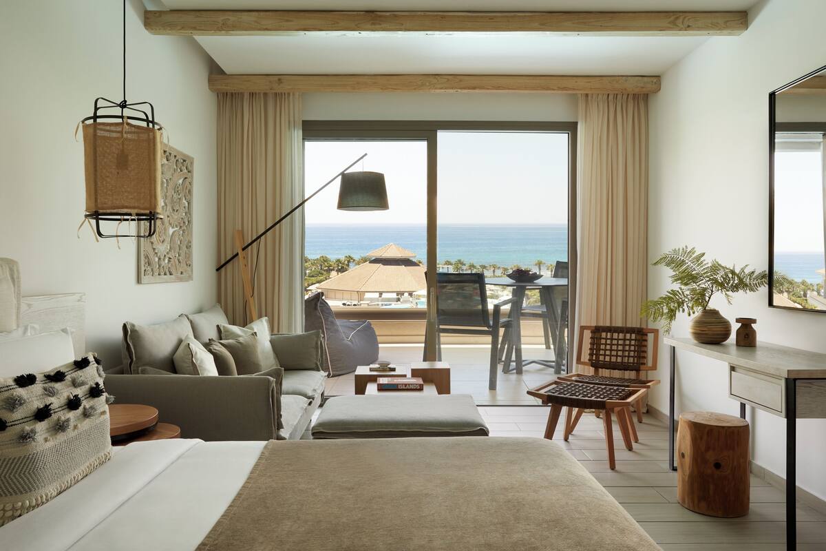 Een moderne slaapkamer met een groot bed, een bank, een bureau en uitzicht op de oceaan.