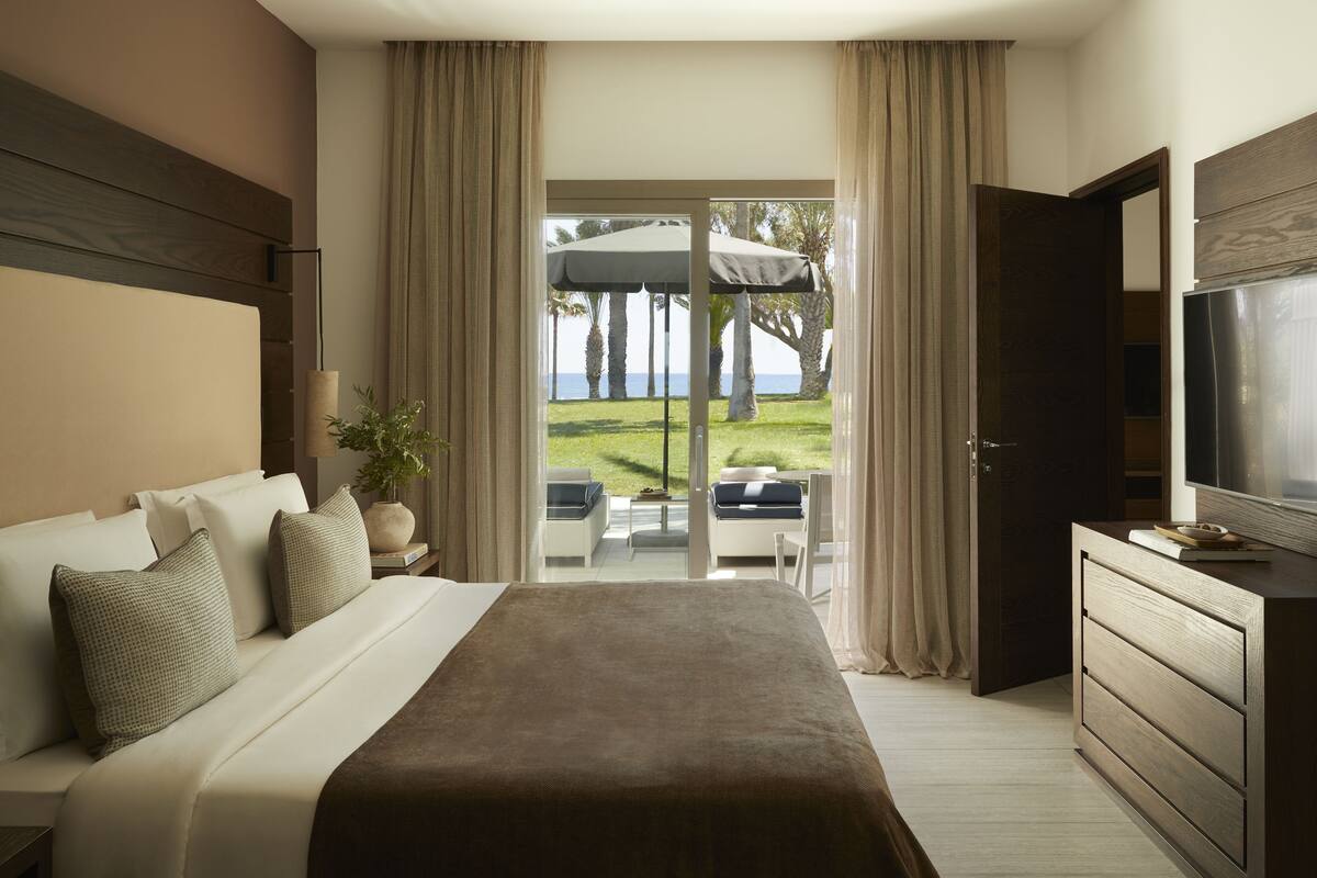 Een hotelkamer met een groot bed, een televisie, een bureau en uitzicht op het omliggende landschap.