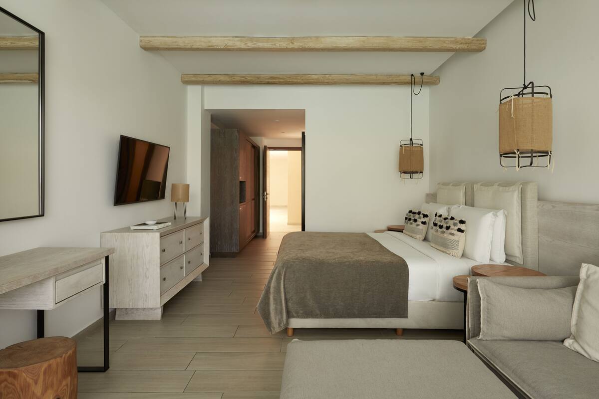 Een moderne slaapkamer met een bed, nachtkastjes, een dressoir en een spiegel.