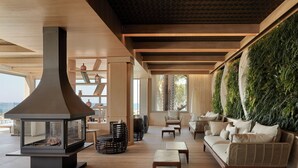 A modern lounge area with a large fireplace, comfortable seating, and a vertical garden wall. - Mare Ayia Napa (Ayia Napa)
